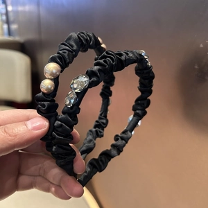 Detailed view of black satin pleated headbands with elegant pearls and crystal rhinestones