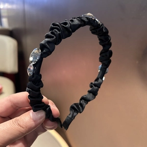 Detail of black satin pleated headband with sparkling oval and diamond-shaped rhinestones