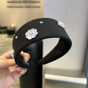 Detail of black wide headband with sequin flower patterns and silver studs for women