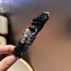 Detail of black pleated satin headband with large sparkling crystal embellishments