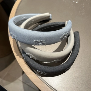 Three padded pearl headbands in blue, beige, and grey with elegant embroidery details