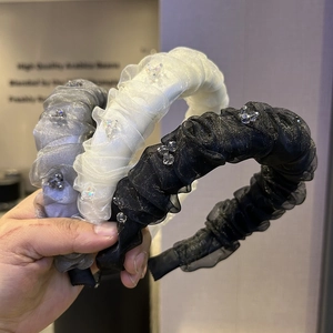 Detailed view of three beaded pleated organza headbands in grey, white and black