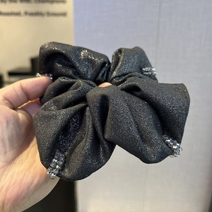 Close-up of black glitter scrunchie with silver crystal beads and textured fabric