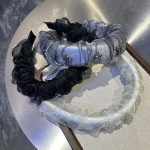 Close-up of handmade beaded organza pleated headbands in black, silver, and beige