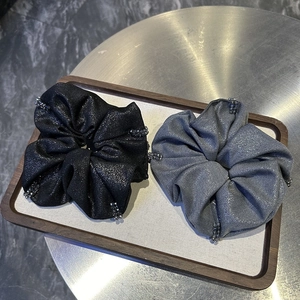 Detail of grey and black beaded scrunchies with metallic shimmer fabric on a wooden tray