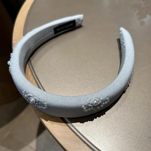 Close-up of light blue padded headband with hand-sewn pearl flower and wave patterns