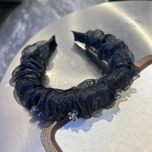 Close-up of black pleated mesh headband with sparkling rhinestone flowers details