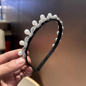 Nahaufnahme eines eleganten Haarreifs mit weißen Perlen und wellenförmigen Strassdetails