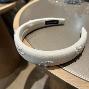 Detail of handmade padded headband with elegant pearl floral patterns and woven texture