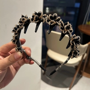Detail of beaded flower headband with integrated black clips and golden crystal accents