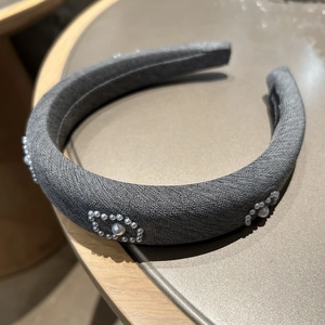 Close-up of thick dark grey tweed headband featuring handcrafted pearl logo detailing