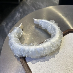 Detailed macro view of white pleated mesh headband with sparkling bead embellishments
