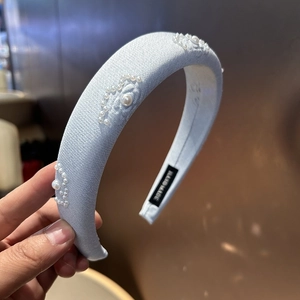 Light blue padded headband with white pearl floral patterns and handmade details