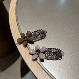 Vue détaillée de deux pinces à cheveux à fleurs vintage avec strass brillants ton Morandi