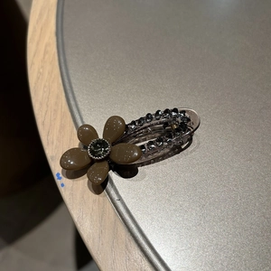 Détail d'une pince à cheveux fleur vintage avec strass et pétales en résine sur bois