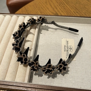 Detail of black beaded flower headband with small hair clips on a jewelry tray