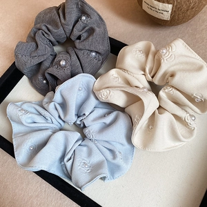 Close-up of pearl-beaded cotton scrunchies with floral embroidery in three soft colors