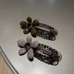 Détail de pinces à cheveux vintage à fleurs et strass en vert olive et mauve clair