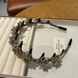 Detail of grey fabric headband featuring crystal flowers and edgy black punk spikes