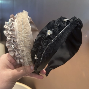 Nahaufnahme von plissierten Haarbändern in Champagner und Schwarz mit glänzenden Herz-Strasssteinen