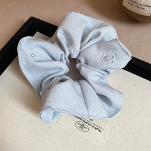 Close-up of light blue scrunchie with embroidered camellia flowers and white pearls