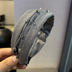Detail view of grey pleated fabric headband with glittering rhinestones for women