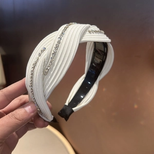Detail of white knotted headband featuring sparkling rhinestone embellishments and fabric texture
