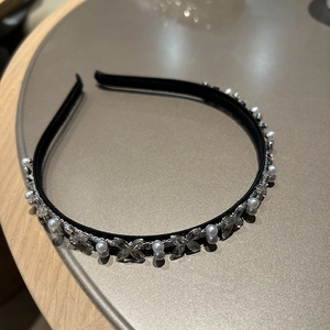 Detail eines schwarzen Stirnbands mit Perlen und Schmetterlingskristallen auf neutralem Grund