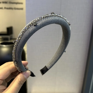 Detailed close-up of a grey satin headband decorated with sparkling crystals and grey gemstones