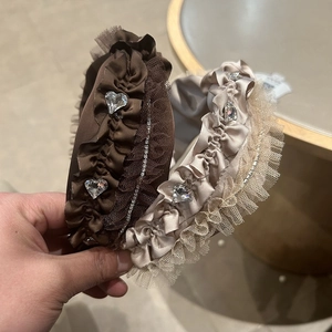 Detail eines Seersucker-Stirnbands mit herzförmigen Strasssteinen und Spitzenstruktur