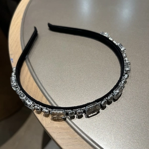 Detail eines eleganten Strass-Haarreifens mit Kristallen auf schwarzem Stoff-Untergrund