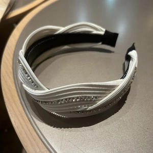 Detail view of white rhinestone wide headband with a crisscross knot and non-slip inner teeth