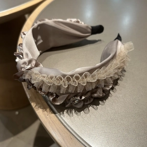 Detail des champagnerfarbenen Satin-Haarreifs mit Rüschen und elegantem Spitzennetz