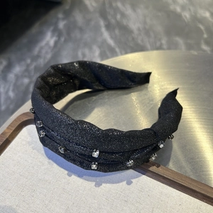 Close-up of black glitter headband with sparkling square crystals on a display tray