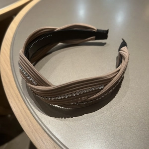 Detailed top view of light brown textured headband with rhinestone cross design and anti-slip teeth