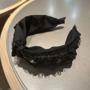 Detail des schwarzen Haarreifens mit plissierter Spitze und funkelnden Strasssteinen