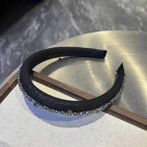 Close-up of padded black headband with dark gray crystal rhinestones and shimmer fabric