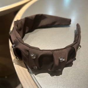 Detailed view of dark brown ruched headband with shimmering fabric and crystal clusters