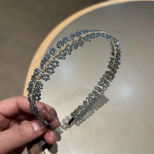 Détail macro d'un serre-tête tressé à la main avec perles bleues et fil doré