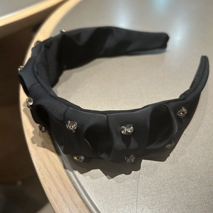 Detail of elegant black pleated headband with sparkling rhinestones and silk texture