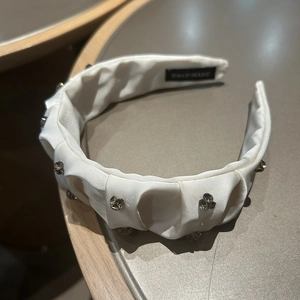 Detail of white pleated satin headband featuring sparkling rhinestones and handmade label