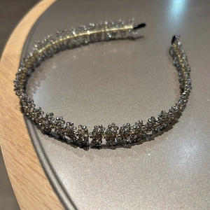 Détail d'un serre-tête tressé en perles grises avec des embouts noirs antidérapants