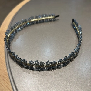 Détail de perles de cristal bleu foncé tissées main sur un serre-tête en métal doré