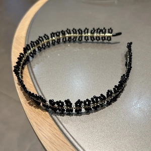 Vue détaillée du serre-tête en métal doré avec motifs fleurs perlées noires élégantes