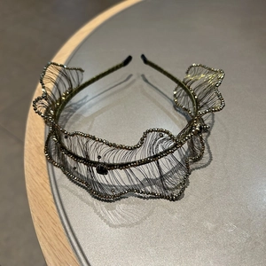 Detailed close-up of a woven luxury crystal headband with bronze wire and black rhinestones