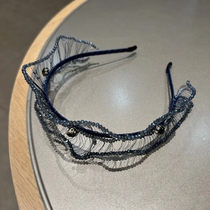 Close-up detail of dark blue beaded headband with woven crystal mesh and wavy design
