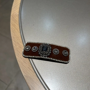 Detailed macro of brown velvet hair clip featuring crystal rhinestones and blue gemstone