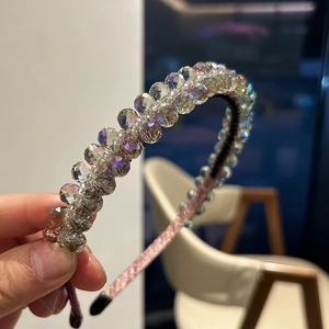 Dettaglio di perle di cristallo sfaccettate colorate avvolte su un cerchietto rosa lucido