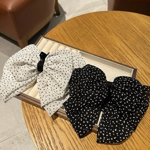 Detail view of retro polka dot chiffon bow hair clips in black and white on a tray