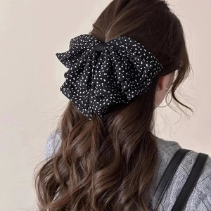 Vintage black and white polka dot oversized mesh bow hair clip on a model with long wavy hair
